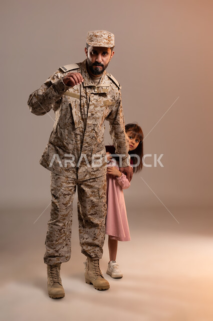 ايماءات تدل على الوقوف بحذر والدفاع عن شئ ما، القوات المسلحة السعودية، بورتريه لرجل عربي سعودي خليجي يرتدي الزي العسكري التقليدي يقوم بحمايه فتاه من خطر ما، الترقب والاستعداد لخطر قادم، التدريبات العسكرية والاستعداد للهجوم، خلفية برتقاليه