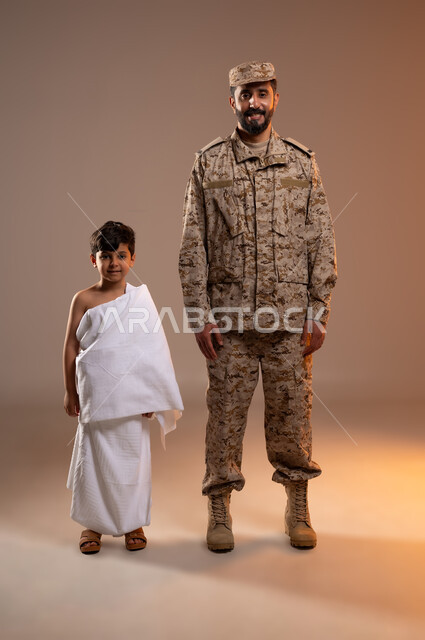 مشاركة اجواء رائعة لعسكري مع صبي ، شهامه رجال الامن بمساعده الحجاج والمعتمرين،  بورتريه لرجل عربي خليجي سعودي يرتدي الزي العسكري يقف مبتسما بجانب صبي معتمر في المسجد الحرام ، تأديه مناسك الحج والعمره بيسر وطمأنينه، خلفيه برتقاليه