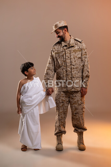مشاركة اجواء رائعة لعسكري مع صبي ، شهامه رجال الامن بمساعده الحجاج والمعتمرين،  بورتريه لرجل عربي خليجي سعودي يرتدي الزي العسكري يقف بجانب صبي معتمر في المسجد الحرام ممسكا بيده، تأديه مناسك الحج والعمره بيسر وطمأنينه، خلفيه برتقاليه
