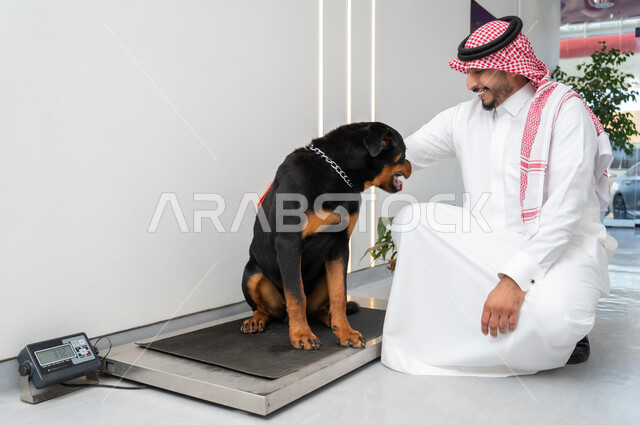 رجل يرتدي الزي التقليدي يقف بجانب الحيوان، المرح واللعب مع الحيوانات الأليفة ، اقتناء وتربية الكلاب ، حيوان ثديي أليف ، مفهوم الرفق بالحيوان ، الشعور بالسعادة أثناء قضاء وقت ممتع في اللعب مع الحيوانات