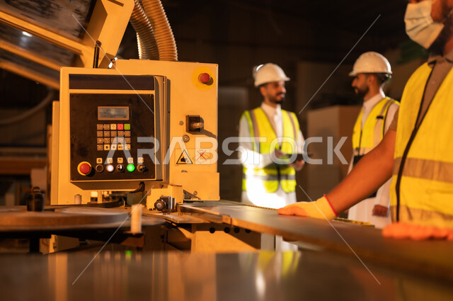 آلة النقش بالليزر, الطباعةعلى القطع الخشبية، التطور والتقدم التقني في صناعة الخشب، العمل في القطاع الصناعي, مهندسين عربيين خليجيين سعوديين يرتديان الخوذة وسترة الحماية يعملان في ورشة نجارة، معمل تصنيع الأثاث المنزلي