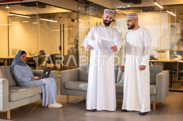 تبادل الأحاديث ووجهات النظر بين الزملاء، بيئة مريحة في الشركات العمانية، مهن ووظائف إدارية في سلطنة عمان، استخدام الأجهزة التقنية الحديثة في إنجاز المهام، مفهوم تدريب وتطوير الموظفين, فريق عمل عربي خليجي عماني داخل مقر الشركة، إيماءات البهجة والسرور