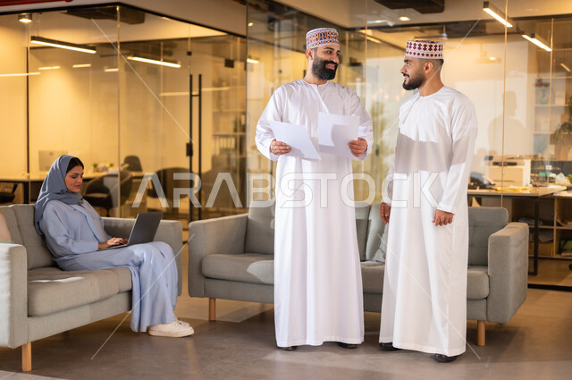 بيئة مريحة في الشركات العمانية، تبادل الأحاديث ووجهات النظر بين الزملاء، مهن ووظائف إدارية في سلطنة عمان، استخدام الأجهزة التقنية الحديثة في إنجاز المهام، مفهوم تدريب وتطوير الموظفين, فريق عمل عربي خليجي عماني داخل مقر الشركة، إيماءات البهجة والسرور