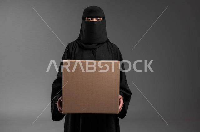 موك اب مستطيل, العروض والإعلانات التسويقية, بورتريه لامرأة عربية خليجية سعودية مسلمة منقبة ترتدي العباءة السوداء تقف باستقامة وتمسك بيديها لوحة بيج فارغة, لوحات توضيحية ووسائل تعليمية, خلفية رمادية