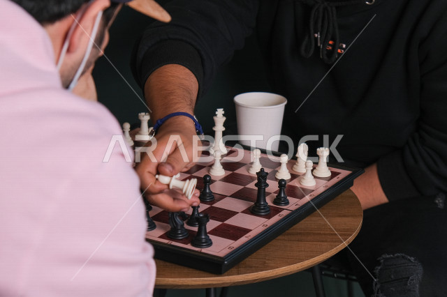 صورة مقربة لشابان خليجيان يلعبان لعبة الشطرنج , صديقان يتحديان بعضهما في لعبة لعبة الشطرنج , لعبة شطرنج لعبة رقمية استراتيجية على رقعة الشطرنج , لعبة شطرنج قديمة
