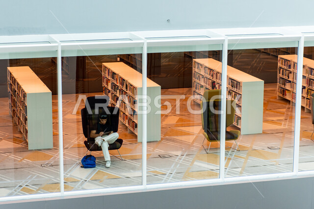 اكتساب المعرفة وتنمية الذخيرة اللغوية، تأمين وسائل الراحة للقراء، مكان للقراء ومحبي العلم والمعرفة، شاب عربي إماراتي خليجي يجلس على كرسي في مكتبة محمد بن راشد الثرية بالمجلات والمعاجم في امارة دبي، المكتبات العلمية في الامارات العربية المتحدة