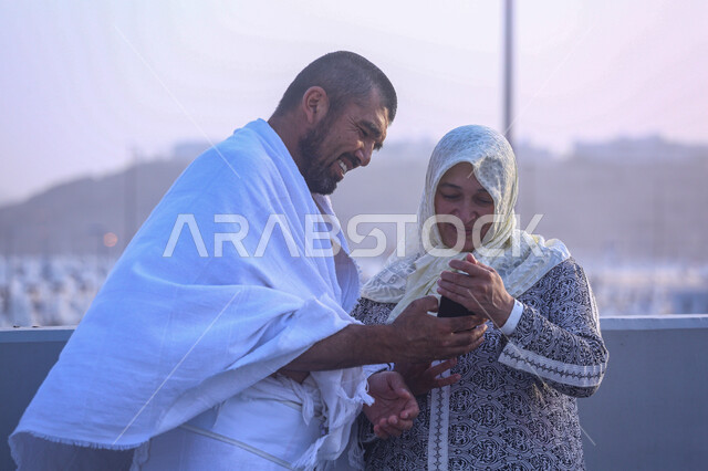 التقاط صور تذكارية، الركن الخامس من أركان الإسلام، زيارة بيت الله الحرام في مكة المكرمة , العبادة والتقرب إلى الله , شاب يرتدي ملابس الاحرام ومعه والدته يقومان بمشاهدة شيء ما عبر الهاتف المحمول، أداء مناسك الحج و العمرة