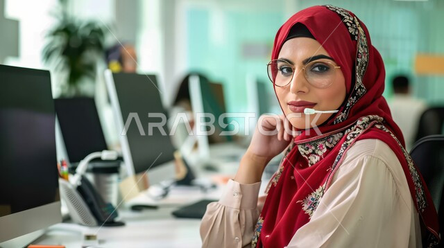 الجلوس وراء المكتب وتنفيذ الأعمال على جهاز الحاسوب, تمكين عمل المرأة في المجتمع السعودي, شابة عربية خليجية سعودية محجبة ترتدي زي الكاجوال وتنظر للكاميرا بإيماءات السرور, التوظيف في مجال خدمة العملاء والرد على الاسئلة والاستفسارات, مهن و وظائف نسائية سعودية
