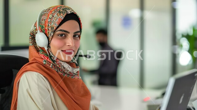 الجلوس وراء المكتب وتنفيذ الأعمال على جهاز الحاسوب, تمكين عمل المرأة في المجتمع السعودي, شابة عربية خليجية سعودية محجبة ترتدي زي الكاجوال وتنظر للكاميرا بإيماءات السرور, التوظيف في مجال خدمة العملاء والرد على الاسئلة والاستفسارات, مهن و وظائف نسائية سعودية