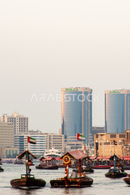 سفينة لأخذ السياح جولة في مياه الخليج, التعرف على معالم المدينة واستكشافها, القوارب الخشبية في المرفأ في منطقة بر دبي بالإمارات العربية المتحدة، الواجهة البحرية السياحية في المدينة القديمة، وسائل النقل عبر البحر, النمو والتطور العمراني للأبراج وناطحات السحاب