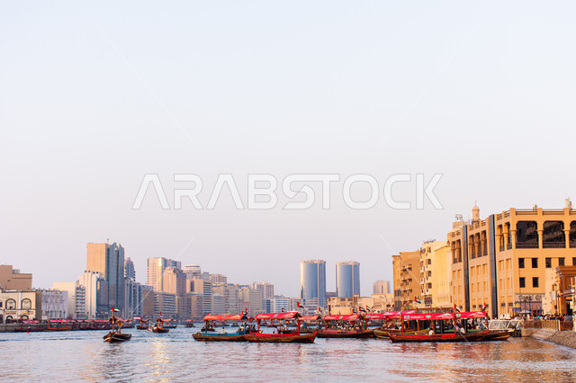 سفينة لأخذ السياح جولة في مياه الخليج, التعرف على معالم المدينة واستكشافها, القوارب الخشبية في المرفأ في منطقة بر دبي بالإمارات العربية المتحدة، الواجهة البحرية السياحية في المدينة القديمة، وسائل النقل عبر البحر, النمو والتطور العمراني للأبراج وناطحات السحاب