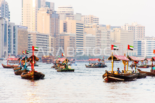 سفينة لأخذ السياح جولة في مياه الخليج, التعرف على معالم المدينة واستكشافها, القوارب الخشبية في المرفأ في منطقة بر دبي بالإمارات العربية المتحدة، الواجهة البحرية السياحية في المدينة القديمة، وسائل النقل عبر البحر, النمو والتطور العمراني للأبراج وناطحات السحاب
