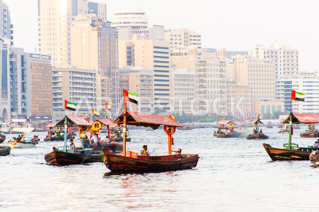 سفينة لأخذ السياح جولة في مياه الخليج, التعرف على معالم المدينة واستكشافها, القوارب الخشبية في المرفأ في منطقة بر دبي بالإمارات العربية المتحدة، الواجهة البحرية السياحية في المدينة القديمة، وسائل النقل عبر البحر, النمو والتطور العمراني للأبراج وناطحات السحاب