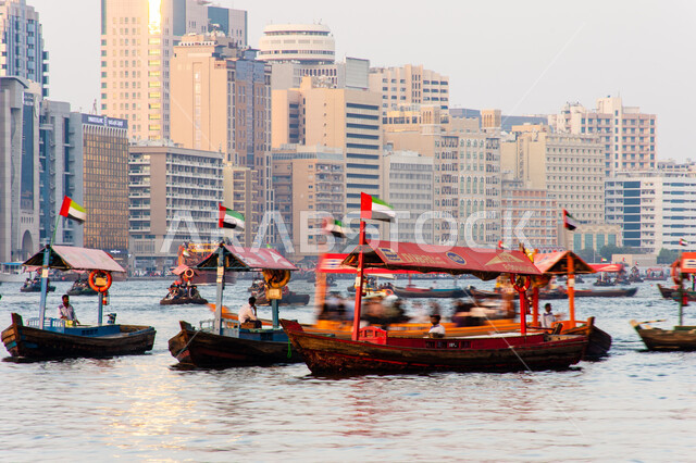 سفينة لأخذ السياح جولة في مياه الخليج, التعرف على معالم المدينة واستكشافها, القوارب الخشبية في المرفأ في منطقة بر دبي بالإمارات العربية المتحدة، الواجهة البحرية السياحية في المدينة القديمة، وسائل النقل عبر البحر, النمو والتطور العمراني للأبراج وناطحات السحاب