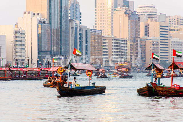 سفينة لأخذ السياح جولة في مياه الخليج, التعرف على معالم المدينة واستكشافها, القوارب الخشبية في المرفأ في منطقة بر دبي بالإمارات العربية المتحدة، الواجهة البحرية السياحية في المدينة القديمة، وسائل النقل عبر البحر, النمو والتطور العمراني للأبراج وناطحات السحاب