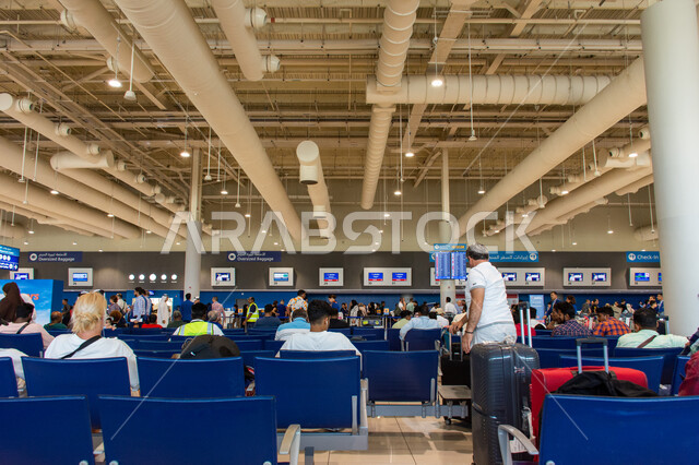 Travelers sitting in the waiting lounges, the distinguished interior decorations and engineering art of Dubai International Airport, electronic guidance screens, tourism and travel in the United Arab Emirates, the most important air hub in the Middle East