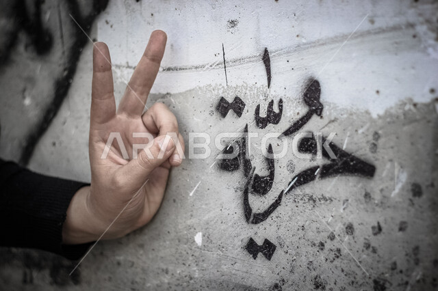 كلمة حرية على حائط قديم مع اشارة النصر باليد ، تحقيق الحرية و السلام