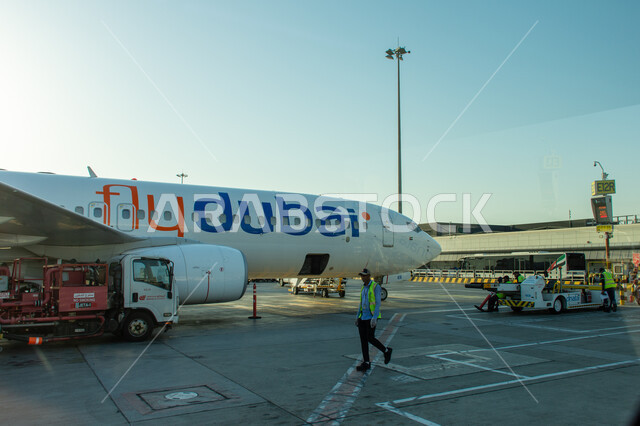 عمال الصيانة والشحن في مدرج مبنى 02 في مطار دبي الدولي، السياحة في إلإمارات العربية المتحدة، شركات وخطوط الطيران الاماراتية، مدرج الهبوط والإقلاع، وسائل النقل والمواصلات الجوية، توفير الخدمات المتطورة لسهولة التنقل بين البلدان، اهم مركز جوي في الشرق الاوسط