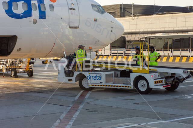 عمال الصيانة والشحن في مدرج مبنى 02 في مطار دبي الدولي، السياحة في إلإمارات العربية المتحدة، شركات وخطوط الطيران الاماراتية، مدرج الهبوط والإقلاع، وسائل النقل والمواصلات الجوية، توفير الخدمات المتطورة لسهولة التنقل بين البلدان، اهم مركز جوي في الشرق الاوسط