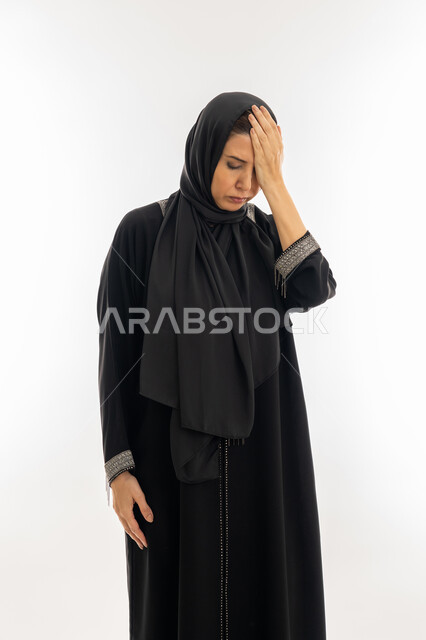 الإرهاق و التعب و الحاجه للعلاج, طلب المساعده للذهاب الى المستشفى، بورتريه مقرب لسيدة عربية سعودية محجبة ترتدي العباءة السوداء تضع يدها على رأسها بتعابير الدوخة وعدم التوازن, امرأة خليجية اماراتية تشعر بالمرض و الصداع, خلفية بيضاء