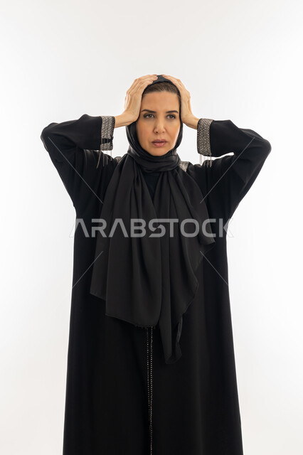 تعابير الصدمة والرغبة بالانتقام ,بورتريه مقرب لامرأة عربيه خليجية اماراتية محجبة ترتدي العباءة السوداء تضع يديها على رأسها بإيماءات الغضب, الامراض النفسيه و الحياه الفاشله, سيدة سعودية تشعر بالندم على فعل شي ما, الوقوع في مصيبة, خلفية بيضاء