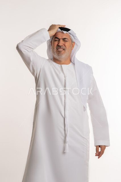 آلام الشقيقة والصداع النصفي، الإحساس بوجع الرأس و الدوخة, الحاجة للعلاج والراحة, إيماءات الألم والتعب والمرض, بورتريه لرجل كبير السن عربي خليجي اماراتي يرتدي الغترة والكندورة يضع يديه على رأسه يشعر بالدوار, خلفية بيضاء