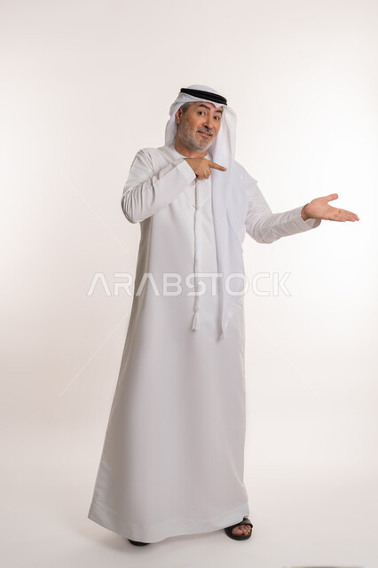 Gestures of confirmation of something, determination towards a certain goal, portrait of an elderly Arab Emirati Gulf man wearing a kandura and ghutra raising his index finger up with an expression of pleasure, pointing to someone, full body image, white background