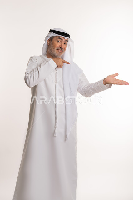 التحديد نحو هدف معين, ايماءات التأكد من شيء ما, بورتريه لرجل مسن عربي اماراتي خليجي يرتدي الكندورة و الغترة يرفع اصبع السبابة للاعلى بتعابير السرور, الإشارة الى شخص ما,  خلفية بيضاء