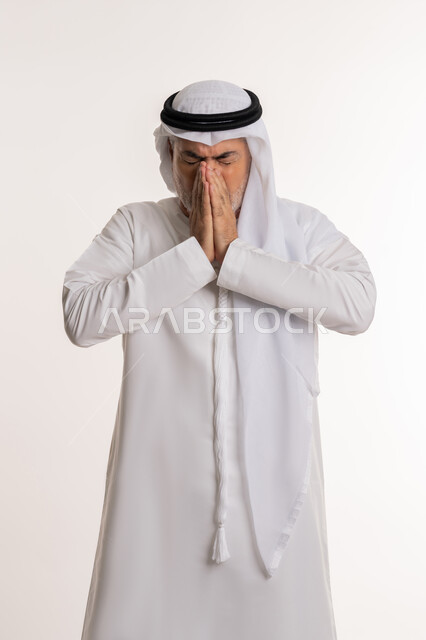 الشعور بالمرض و الزكام والحاجة الى العلاج والدواء, التهاب الأنف التحسسية, بورتريه من الجانب لرجل كبير بالسن عربي اماراتي خليجي يرتدي الغترة والكندورة يضع يديه على وجهه بإيماءات العطاس, خلفية بيضاء