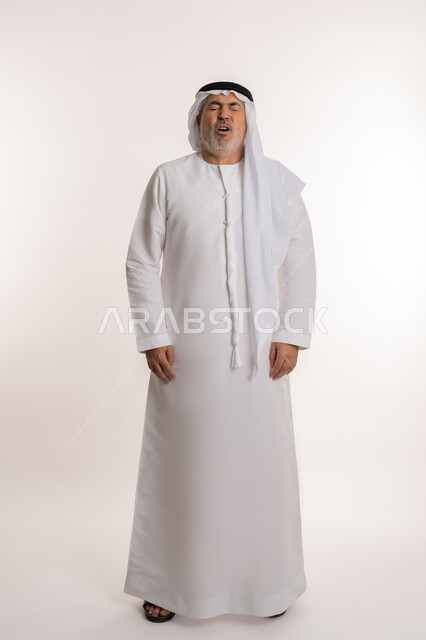 الشعور بالمرض و الزكام والحاجة الى العلاج والدواء, التهاب الأنف التحسسية, بورتريه لرجل كبير بالسن عربي اماراتي خليجي يرتدي الغترة والكندورة يقف بإيماءات العطاس, صورة الجسم بالطول الكامل, خلفية بيضاء