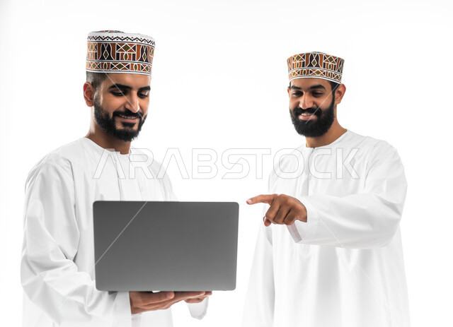 المشاركة في إنهاء الأعمال، مفهوم الجد والاجتهاد، بورتريه لشابان عربيان خليجيان عمانيان يرتديان الدشداشة والكمه تظهر عليهما علامات الفرح والسرور، النقاش والحوار في شؤون العمل، استخدام التقنيات الحديثة لإنجاز المهام، خلفية بيضاء