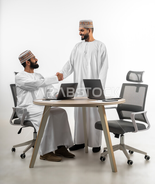 الابتسامة في وجه الآخرين والرقي في المعاملة، حسن الاستقبال و المصافحة عند رد السلام، بورتريه لشابان عربيان خليجيان عمانيان يرتدي كل منهما دشداشة بيضاء وكمه  يقابلان بعضهما بايماءات السرور، خلفية بيضاء