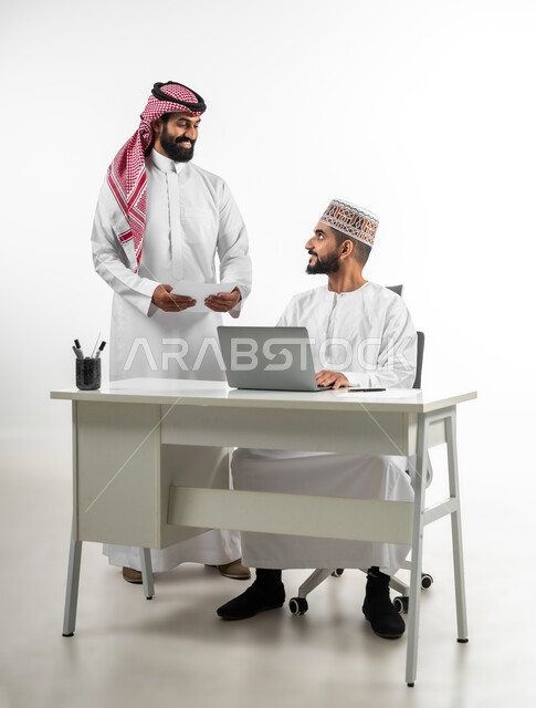 اللطف والرقي في التعامل مع الموظفين، بورتريه لرجل عربي سعودي يرتدي الدشداشة والشماخ يقوم بشرح طبيعة الاعمال لرجل عمامي بطريقة سلسة ولطيفة، ايماءات السعادة والسرور، اجزاء عملية وإنجاز مهام, خلفية بيضاء