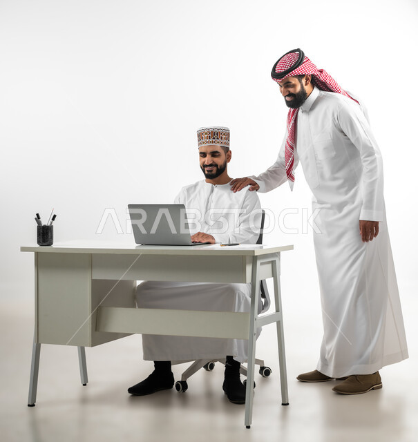 اللطف والرقي في التعامل مع الموظفين، بورتريه لرجل عربي سعودي يرتدي الدشداشة والشماخ يقوم بشرح طبيعة الاعمال لرجل عمامي بطريقة سلسة ولطيفة، ايماءات السعادة والسرور، اجزاء عملية وإنجاز مهام, خلفية بيضاء