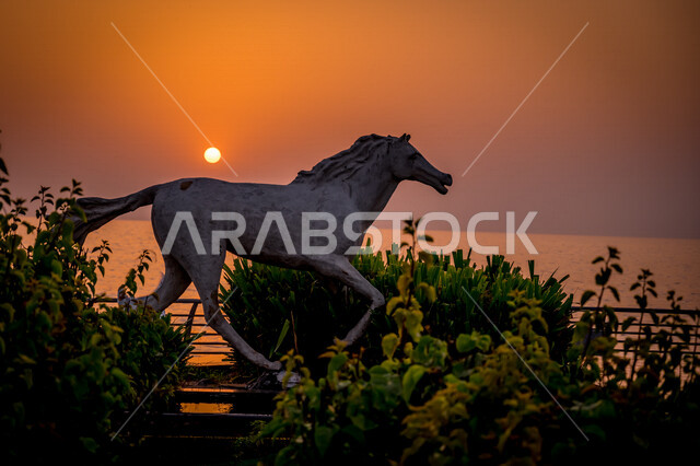 A stone statue in the shape of a purebred Arabian white horse located in Jeddah Corniche, Saudi Arabia, sunset