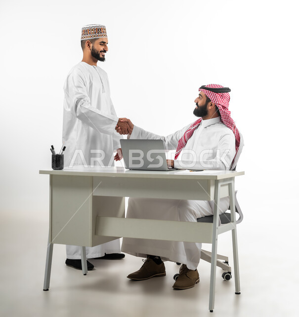 الابتسامة في وجه الآخرين والرقي في المعاملة، المصافحة ورد السلام، بورتريه لشابان عربيان سعودي وعماني يرتدي كل منهما دشداشة بيضاء  يقابلان بعضهما بايماءات السرور، الجسم بالطول الكامل، خلفية بيضاء