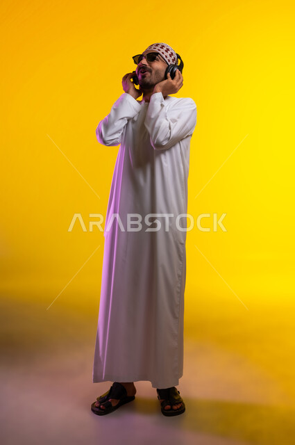Artistic singing talents, gestures and expressions to blend in with the song, a portrait of an Arab Gulf Omani man wearing a dishdasha and a sleeve listening to music through headphones, gestures indicating listening and listening to songs using a headphone, interacting with musical melodies, a yellow background.