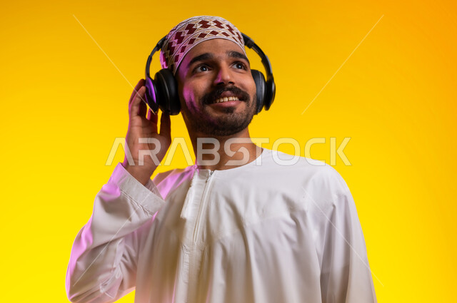 Artistic singing talents, gestures and expressions to blend in with the song, a portrait of an Arab Gulf Omani man wearing a dishdasha and a sleeve listening to music through headphones, gestures indicating listening and listening to songs using a headphone, interacting with musical melodies, a yellow background.