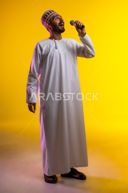 تقديم العروضات المسرحية، الاستمتاع بأداء المواهب الصوتية، بورتريه  لشاب عربي خليجي عماني يرتدي الدشداشه والكمه يمسك بيده المايكروفون، إيماءات وتعابير الاندماج والتفاعل مع الموسيقا، تسجيل مقطع صوتي غنائي، خلفيه برتقاليه