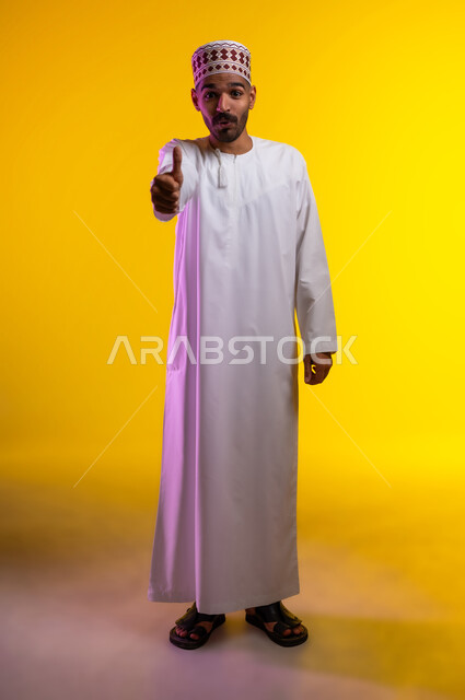 ايماءات تدل على الموافقة والقبول، بورتريه لرجل عربي خليجي عماني يرتدي الدشداشة والكمه يشير باصبع الابهام للاعلى تظهر عليه تعابير الفرح والسرور، الرضى وعدم الرفض، خلفية برتقاليه