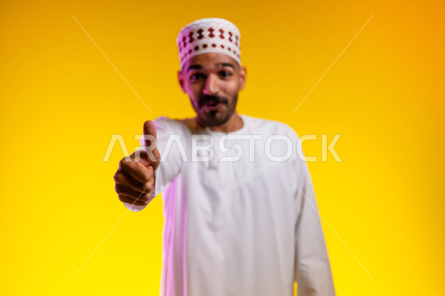 ايماءات تدل على الموافقة والقبول، بورتريه لرجل عربي خليجي عماني يرتدي الدشداشة والكمه يشير باصبع الابهام للاعلى تظهر عليه تعابير الفرح والسرور، الرضى وعدم الرفض، خلفية برتقاليه