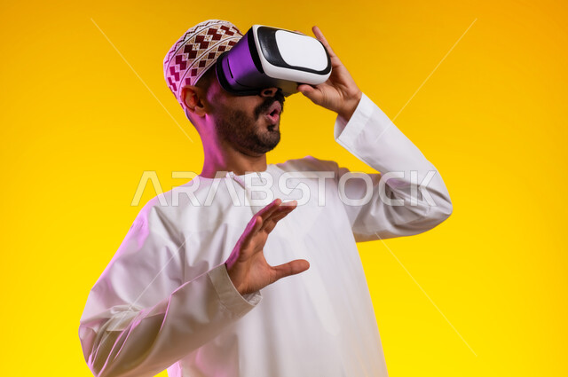 التطور التقني والتكنولوجي, المتعة و التسلية بالمشاهدة عبر نظارة الواقع الافتراضي، بورتريه لشاب عربي خليجي عماني يرتدي الدشداشه والكمه ينظر من خلال نظارات ثلاثية الأبعاد (الفي ار), الاندماج ومحاكاة العالم الخيالي والنظر الى الافلام الواقعيه، خلفيه برتقاليه