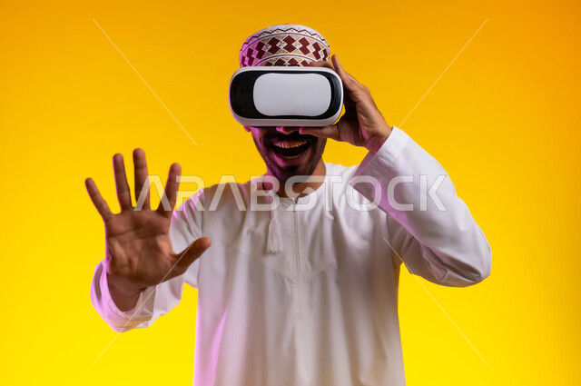 التطور التقني والتكنولوجي, المتعة و التسلية بالمشاهدة عبر نظارة الواقع الافتراضي، بورتريه لشاب عربي خليجي عماني يرتدي الدشداشه والكمه ينظر من خلال نظارات ثلاثية الأبعاد (الفي ار), الاندماج ومحاكاة العالم الخيالي والنظر الى الافلام الواقعيه، خلفيه برتقاليه