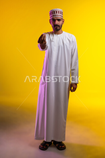حركة يد تعني خفض الصوت والهدوء، ايماءات وجه ويدين تدل على محاولة تهدئة نقاش حاد، بورتريه لرجل عربي خليجي عماني يرتدي الدشداشة والكمه تظهر عليه علامات الانزعاج وعدم الراحة، طريقة الطلب بأدب واحترام، خلفية برتقاليه