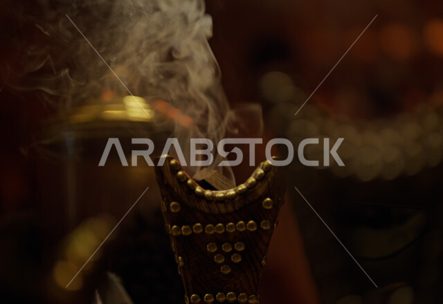 منتج وطني محلي سعودي، منظر الدخان المنتشر من البخور، أصالة العادات والتقاليد في المملكة العربية السعودية، التعطر والتطيب باطيب الروائح والعطور، خشب العود الفاخر والفحم، صورة مقربة لمبخرة تقليدية مزخرفة في مكان تراثي