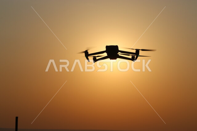 القدم التقني والتكنولوجي لأدوات التصوير، استعمال تقنيات أجهزة التصوير الحديثة، صورة ظلية لطائرة درون تحلق في سماء المملكة العربية السعودية وقت غروب الشمس، سالويت