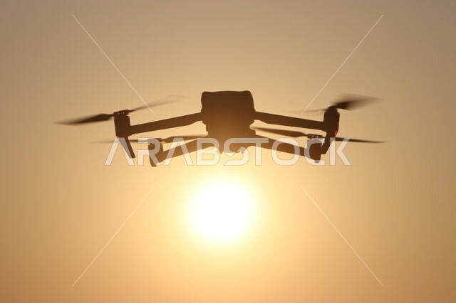 Technical and technological development of photography tools, use of modern photography techniques, silhouette of a drone flying in the sky of the Kingdom of Saudi Arabia at sunset, Saluit