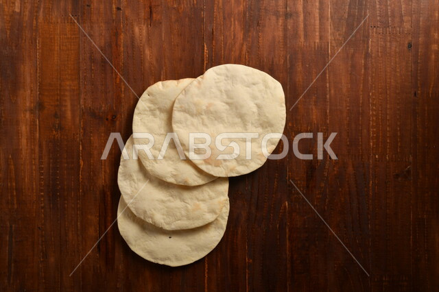 A number of delicious Arabic bread loaves, freshly baked, placed on a wooden surface