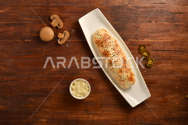 طبق فطور لذيذ ، فطيرة جبنة مخبوزة شهية ، جبنة مبشورة ، عدد من قطع الفطر المقطعة ، فلفل هالبينو، مأكولات عربي