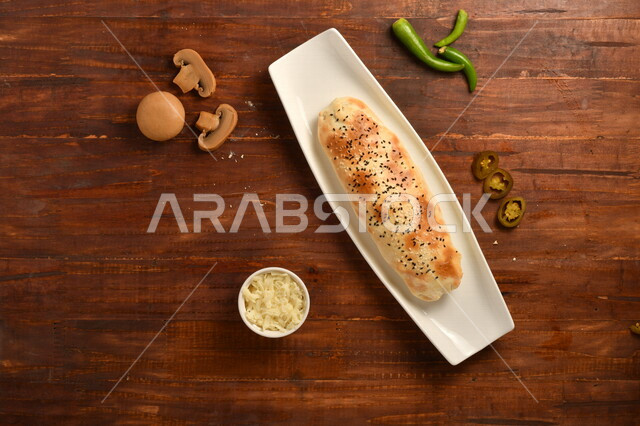 طبق فطور لذيذ ، فطيرة جبنة مخبوزة شهية ، جبنة مبشورة ، عدد من قطع الفطر المقطعة ، فلفل هالبينو، مأكولات عربي